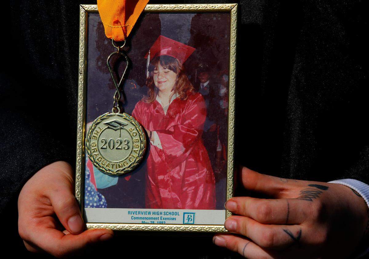 Shannon Nourse, 19, holds a River View High School graduation photo from showing her mother, Chantal Harrison, at the 1982 commencement ceremony. She has overcome the death of her mother last year and other struggles to be one of about 40 graduates from the online Endeavor High School in 2023.