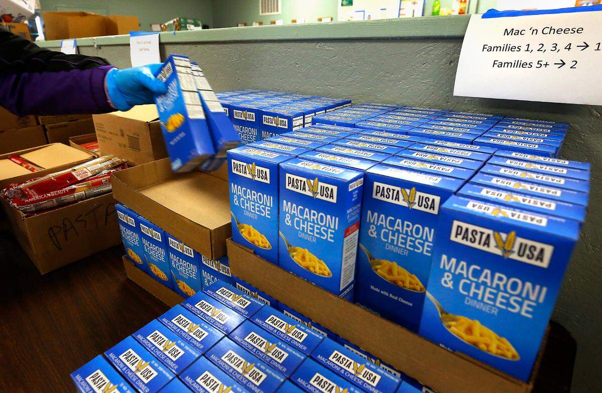 A volunteer “shopper” at the Tri-Cities Food Bank downtown Kennewick location at 420 W. Deschutes Ave. grabs boxes of macaroni and cheese while filling a shopping cart with a variety of food items based on a list generated when the client checks in at the facility.