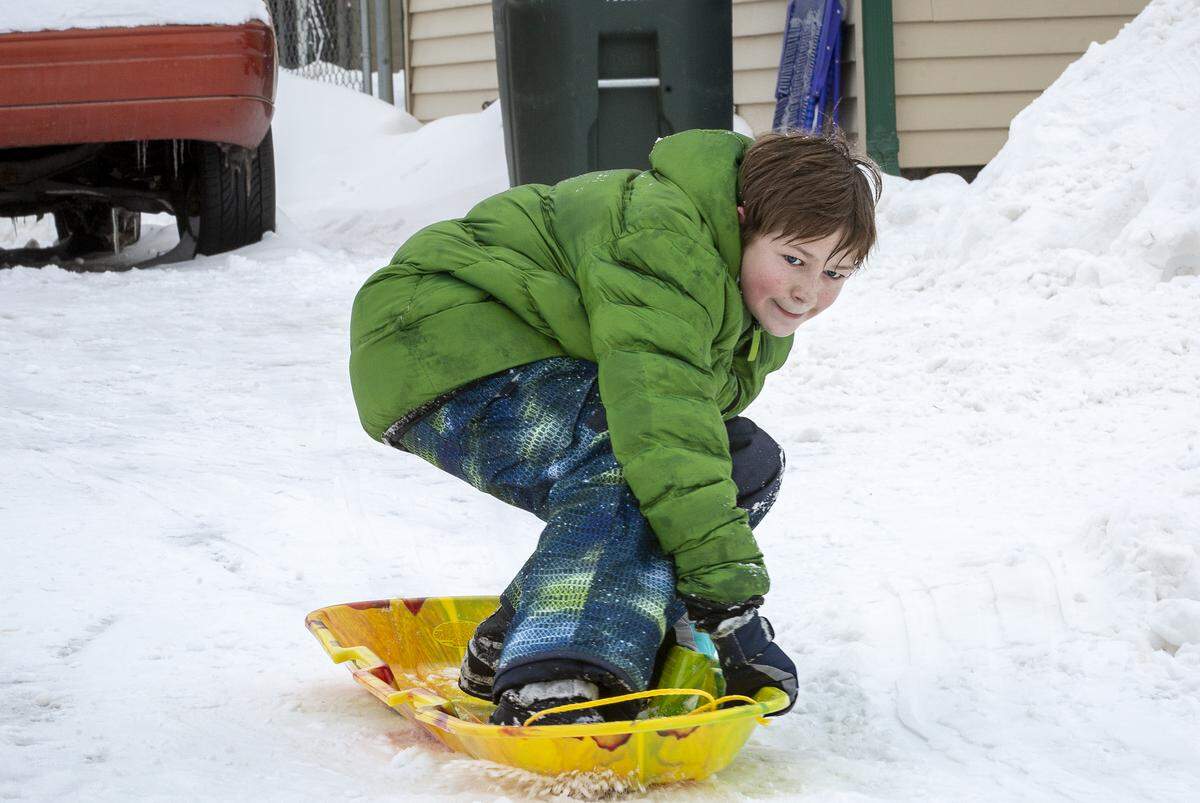 Ashleigh Flint, 12, surfs on his sled down his driveway in Richland on Tuesday.