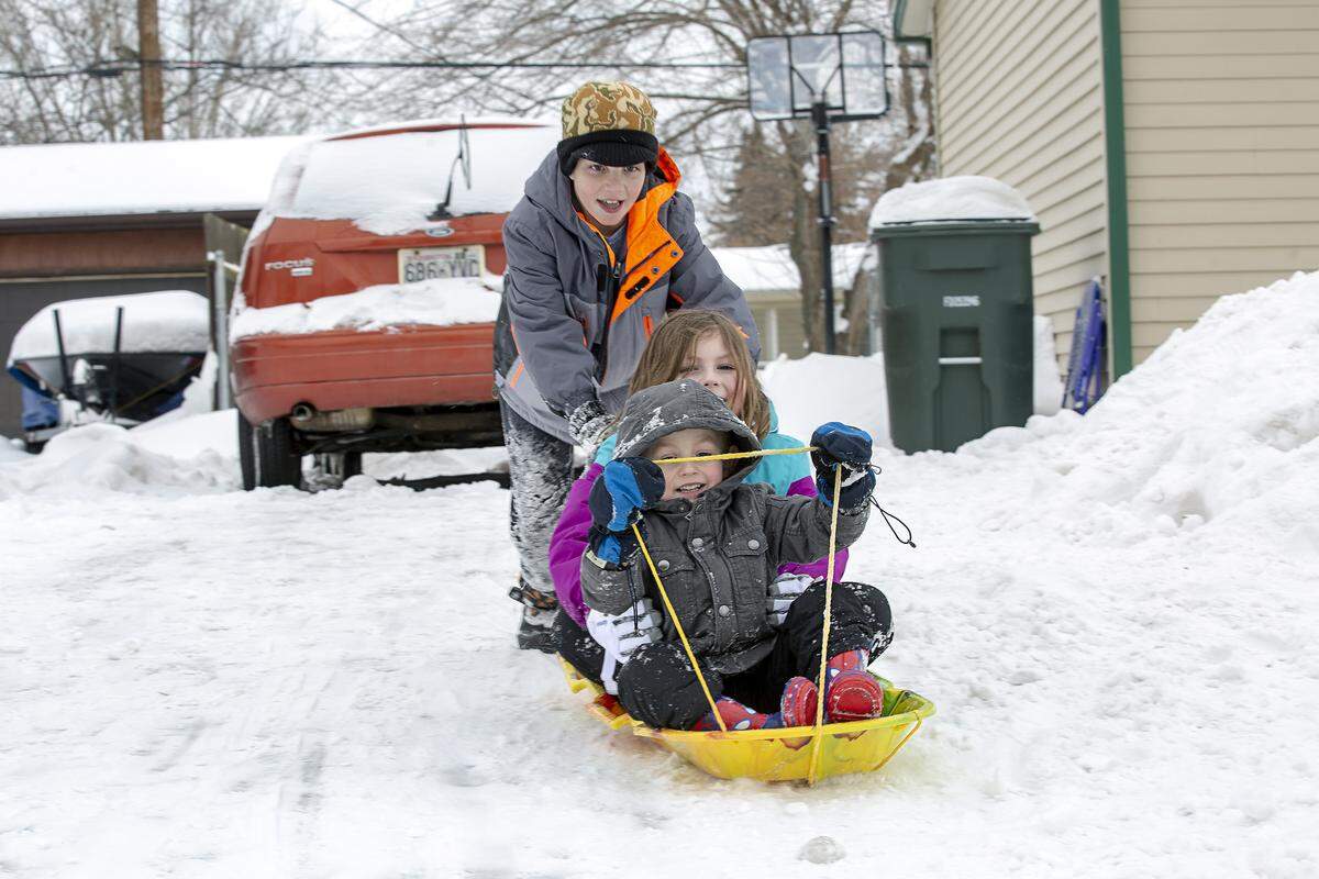 Friends Garrett Huff, 10, pushes the sled as Zoe Call, 7, and Eli Warnick, 5, ride on it on Tuesday in Richland after classes were canceled by the weather.