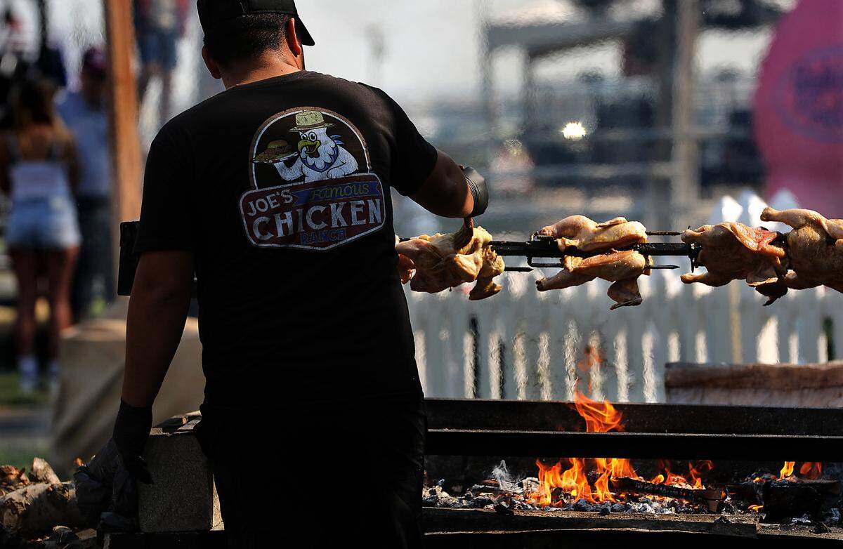 Whole chickens are basted while cooking over hot coals at the Joe’s Famous Chicken Shack food booth at the Benton Franklin Fair & Rodeo at the fairgrounds in Kennewick.