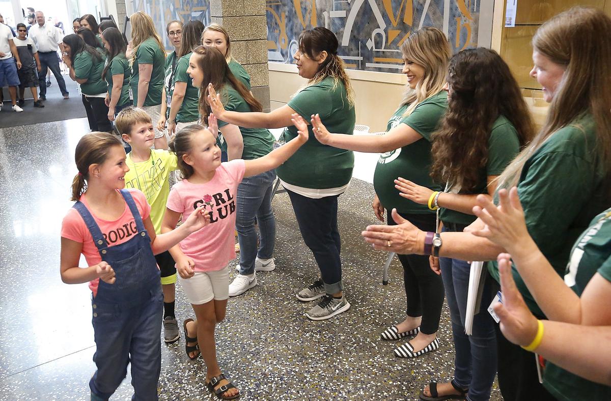 Students Emilia Smith, Ryan Smith, and Ashtyn Ducat, from left, receive a rousing welcome Thursday morning from Fuerza Elementary staff at the new school’s ribbon-cutting ceremony in Kennewick. The dual-language school, built on the former campus of Desert Hills Middle School, has 30 classrooms. It cost $22.7 million. Watch a video at: tricityherald.com/video