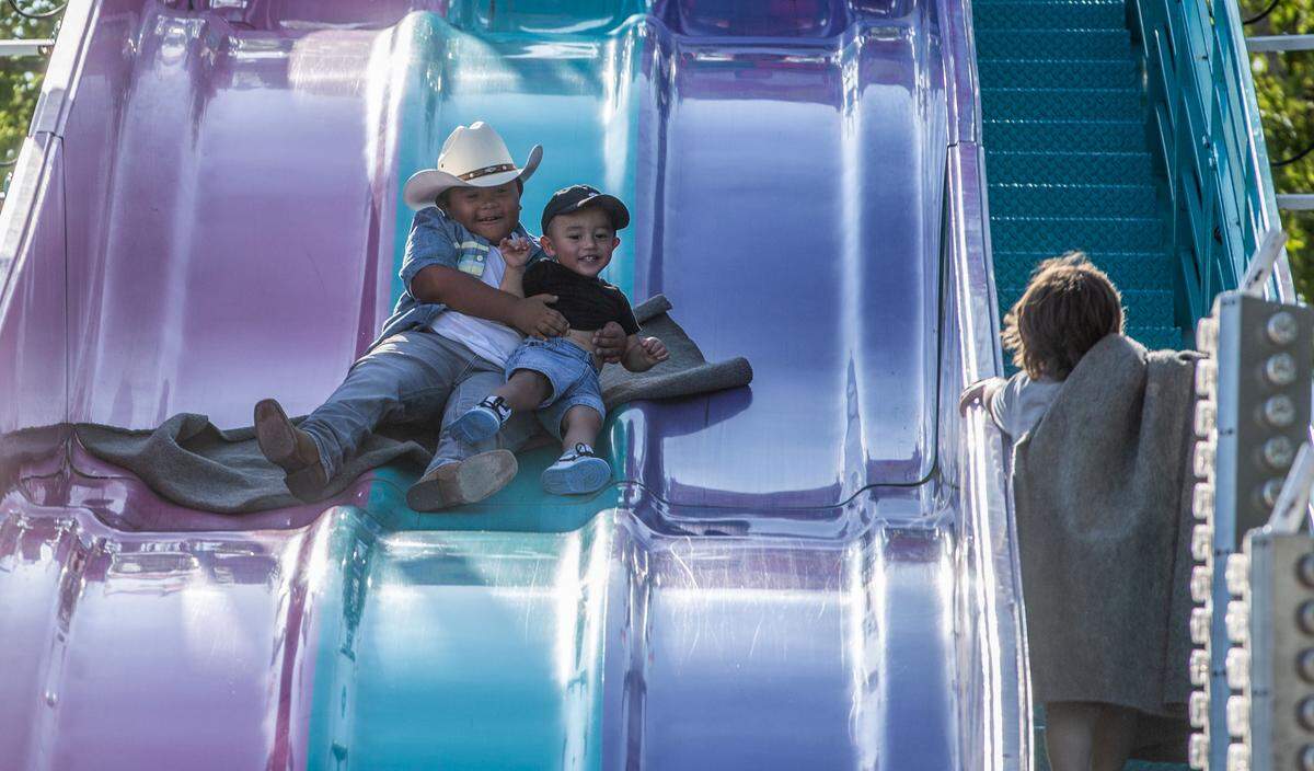 Lino Molina, 8, goes for a quick ride down a slide with his nephew Ermias Quinones, 1, during a family outing to the Benton Franklin Fair & Rodeo in Kennewick.