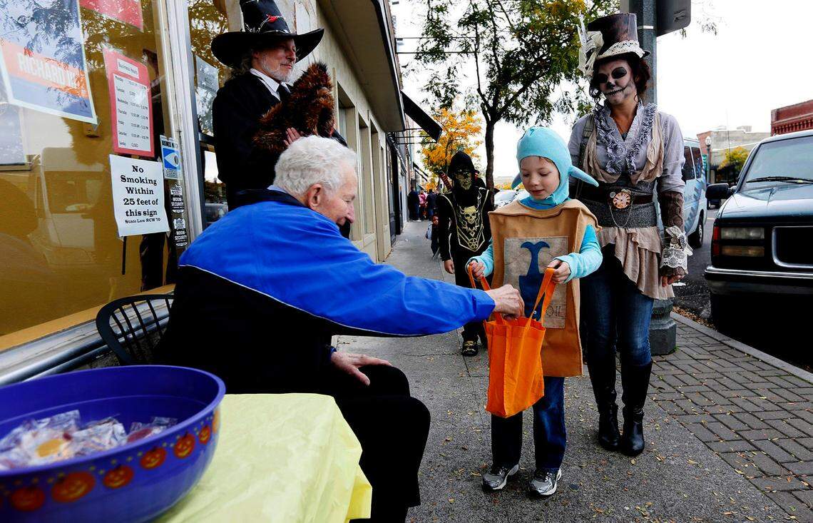 Wes Door handing out candy during the 2014 annual Historic Downtown Kennewick Partnership Trick or Treat event. He’s shown seated next to his son, Jim Door, who is standing in front of his business called JD’s Time Center in downtown Kennewick