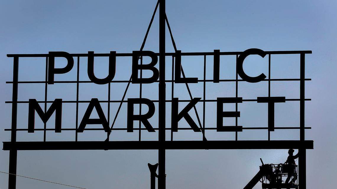 An employee of Yesco custom signs works from a bucket truck welding and grinding on a new sign being installed for the Public Market at Columbia River Warehouse in downtown Kennewick.