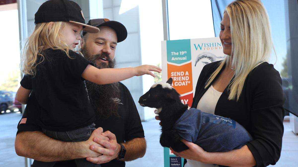 Calvin George and his father, Gerrad, meet a baby goat, Taco. Gerrad’s daughter, Millie, is a Wish Kid at The Wishing Star Foundation.