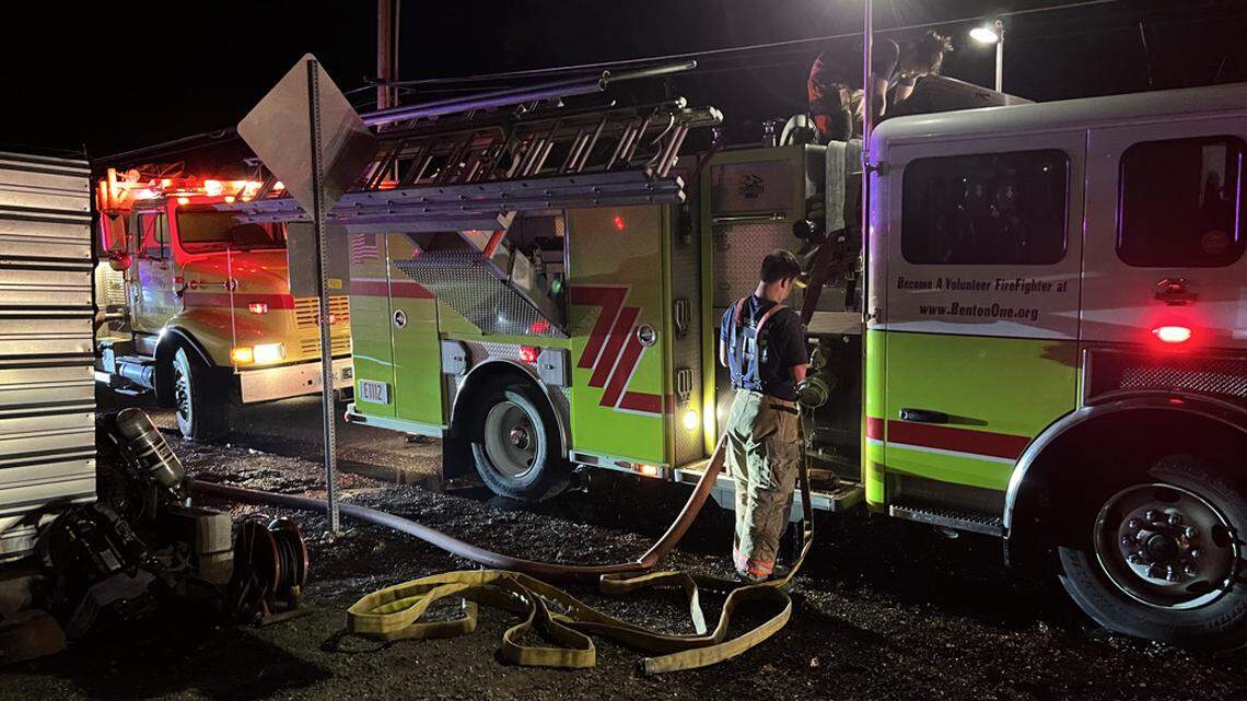 A firefighter with Benton County Fire District 1 rolls up a hose early Sunday morning after a Saturday night mobile home fire in Finley.