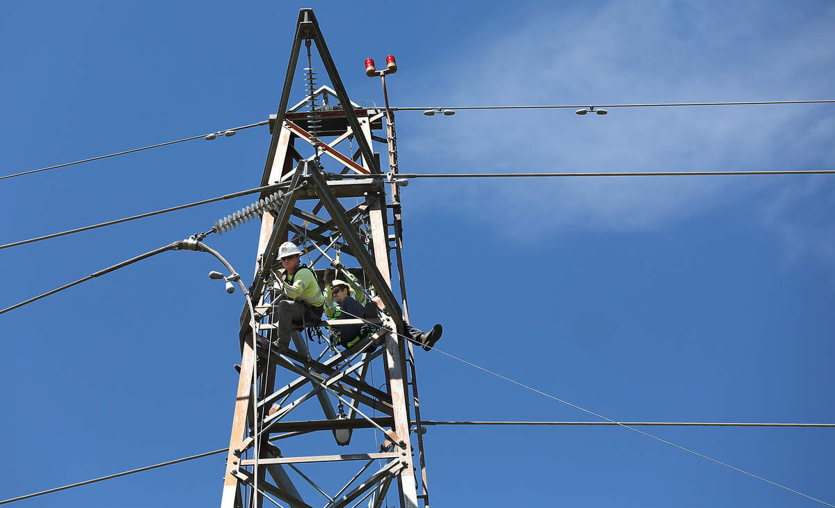 DJ's Electrical employees work near the top of the 140-foot electrical tower on the Kennewick shoreline Tuesday installing a pulley for a rope that will be used in the process of replacing the high tension power line damaged by last week's floatplane crash.