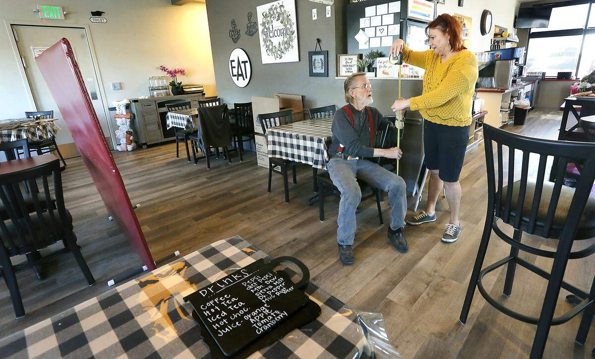 Roger Pearson is helped by his wife, Nancy Galstad measure inside Hill’s Restaurant & Lounge in Kennewick to make dividers he designed and built to give diners more protection. Watch a video at: tricityherald.com/video