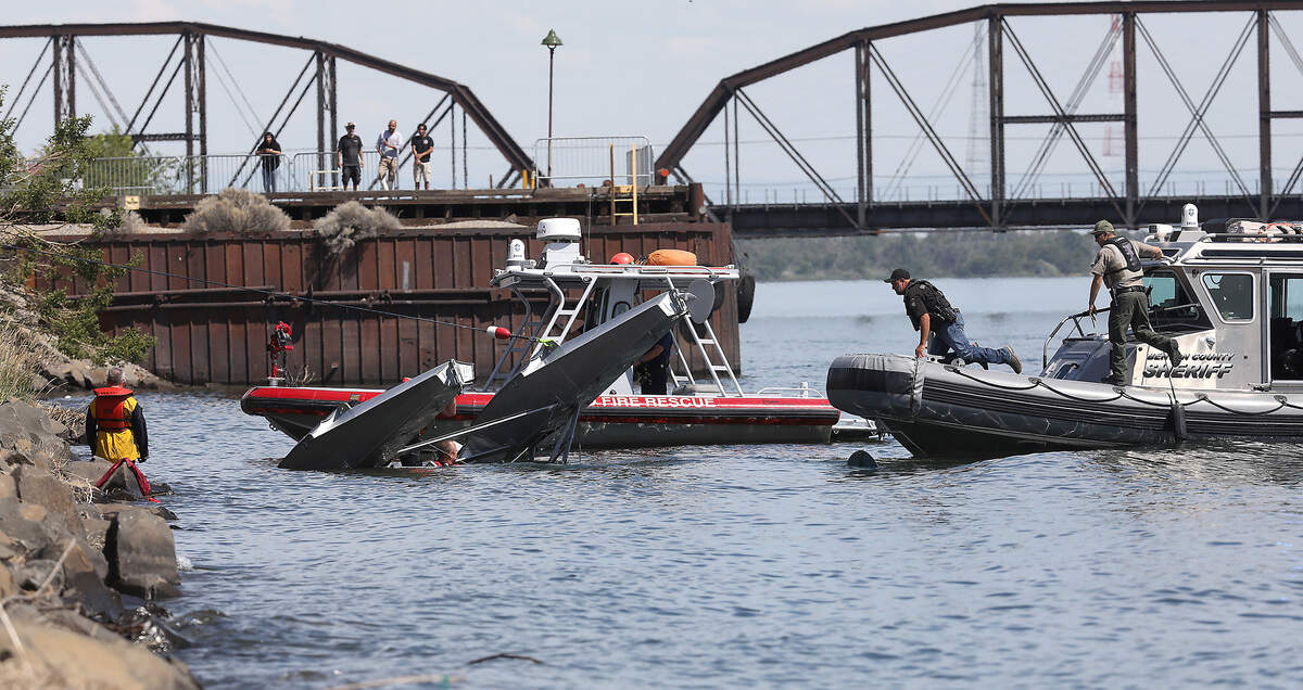 Rescue workers and rescue boats work on the submerged flipped floatplane.