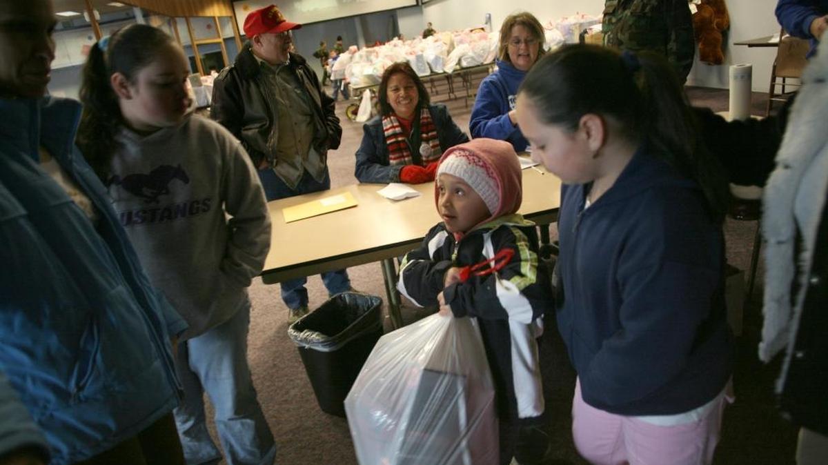 Lizette Alvarez looks at her mother, Cipriana Chavez, before stealing a glimpse of presents her family received from Marine Corps Reserve Toys for Tots in Pasco in this file photo.