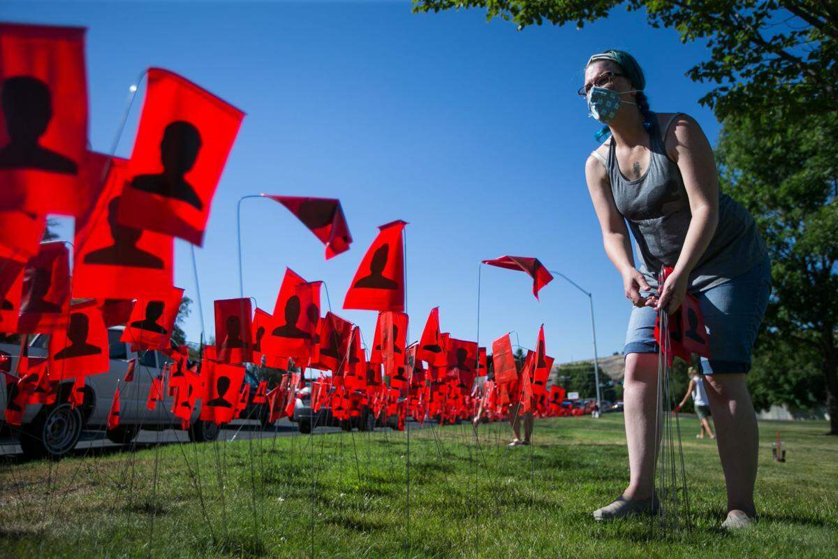 Leola Reeves places a red flag in the ground Tuesday near Chesterley Park in Yakima. A project in Yakima County is illustrating the imact of COVID-19 with a red flag for each of the 9,968 county residents who have tested positive and black flags for the 194 people who have died due to the coronavirus.