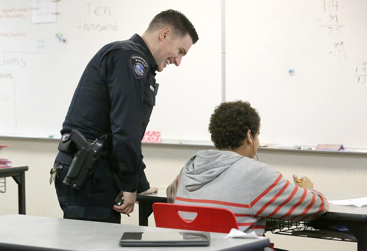 School Resource Officer Tim Harris, with the Kennewick Police Department, shares a light moment with student Chris Jackson during an informal classroom visit recently at Highlands Middle School in Kennewick. Watch a video at: tricityherald.com/video
