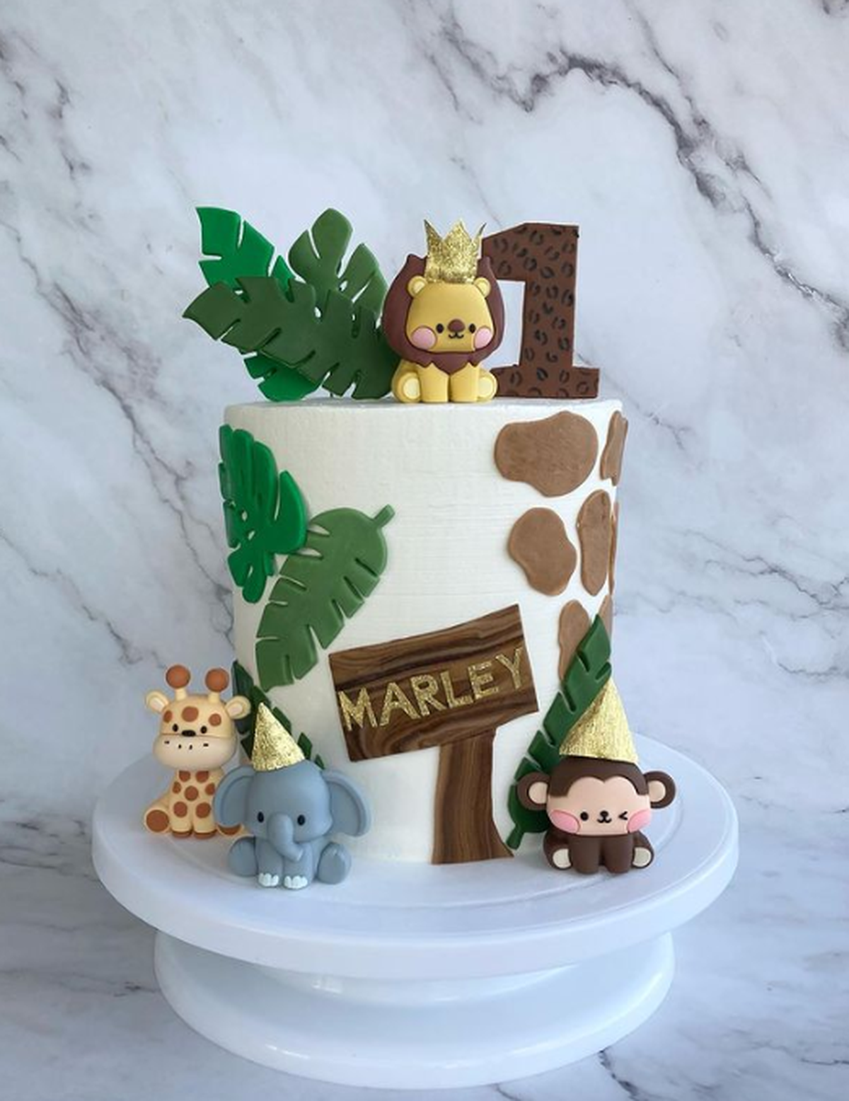 Jungle-themed birthday cake for one-year-old by @CakeWand featuring some party animals.