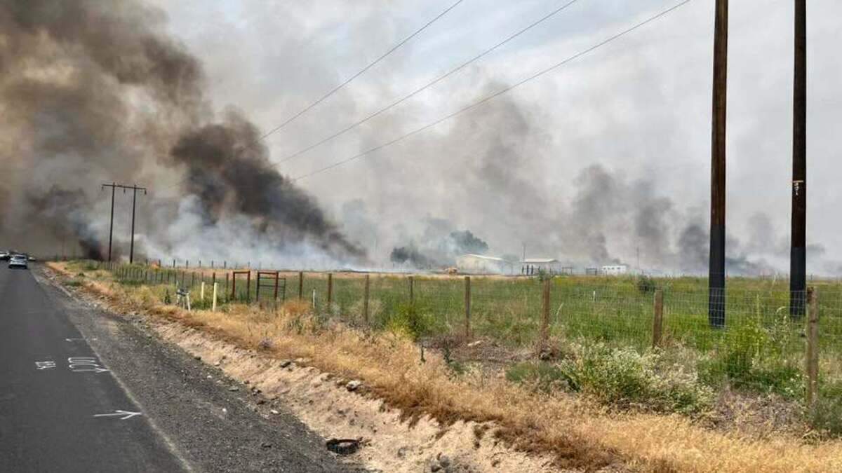 Firefighters are battling a blaze north of Benton City that has threatened homes and shut down roads.
