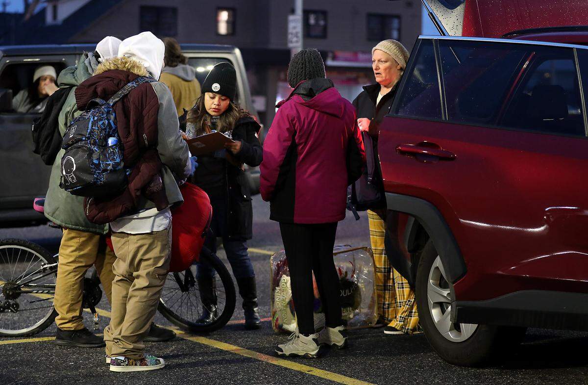 Maria Perez, a Kadlec community health worker, fills out a Point in Time field survey form while talking with two homeless men named Smokey and Pichon in the parking lot of downtown Pasco grocery store. 