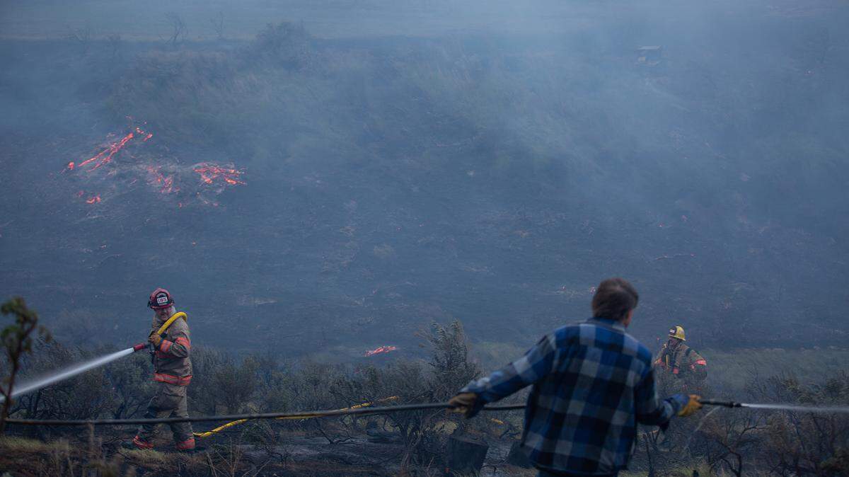 Rich Hempel sprays a garden hose with the goal of protecting his neighbors home as firefighters work to extinguish the blaze behind his neighbor's home Friday evening.