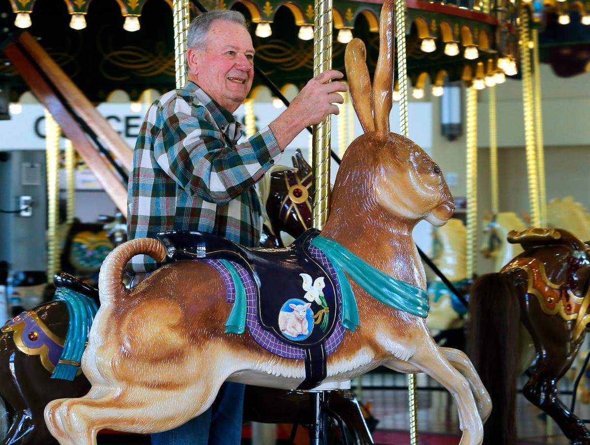 Artist Mike Thorton of Richland takes a ride with his newest carving for the Gesa Carousel of Dreams, an Easter bunny named Sir Hops-a-Lot.