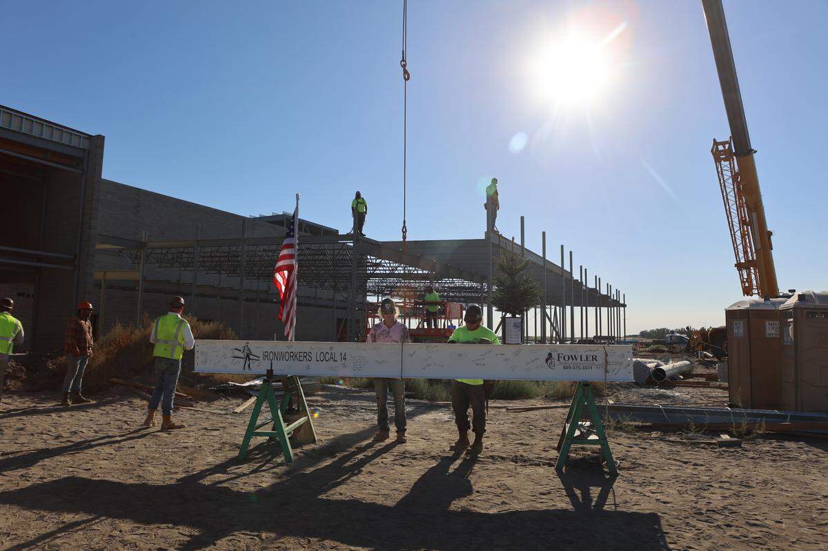Construction workers prepare the final beam of the Sageview High School structure to be lifted in the air.