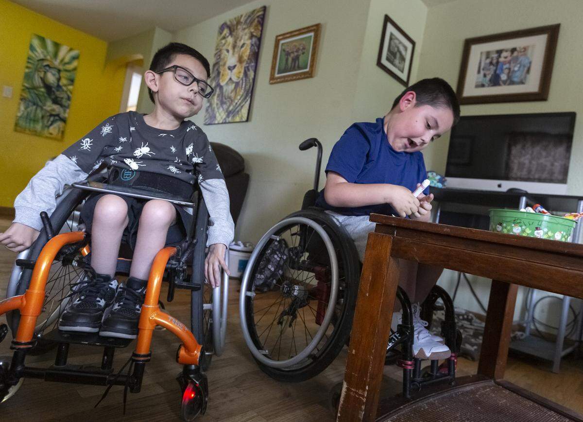 Five-year-old Hendrix Ramos, left, watches his twin brother Harper color inside of their Pasco home. The twins love playing games on their tablet, drawing, Pokemon and are “sneaker heads.”