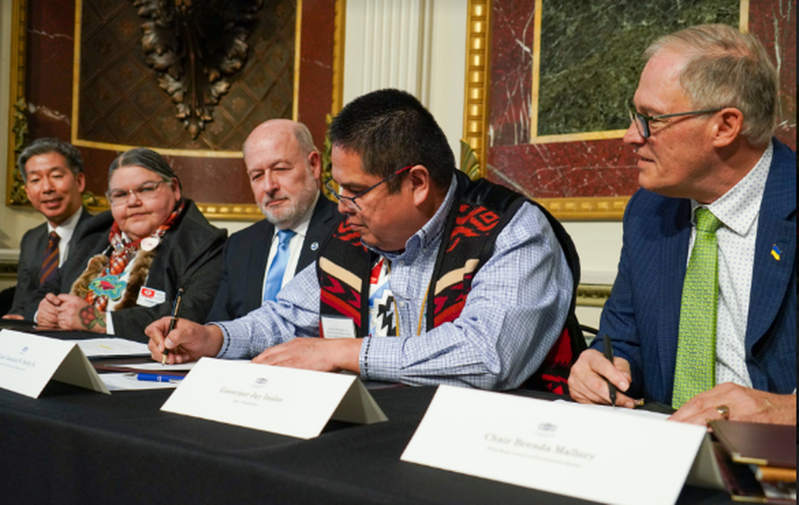 Washington Gov. Jay Inslee, right, watches as Chairman Jonathan Smith of the Confederate Tribes of Warm Springs signs the Columbia River Basin restoration agreement at the White House.