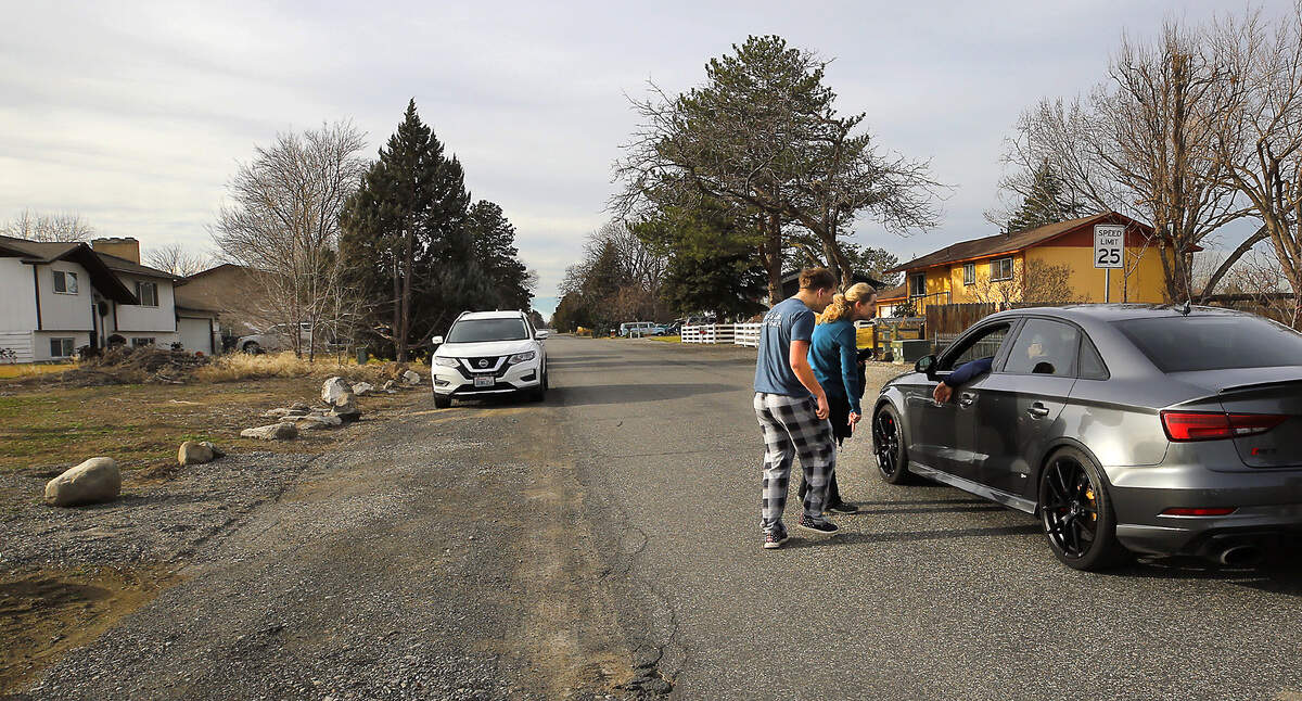 Lisa Julson and her son, Parker, 19, inform a neighbor Tuesday afternoon about a less restrictive alternative facility, for housing for registered sex offenders, is scheduled for a house in Kennewick.