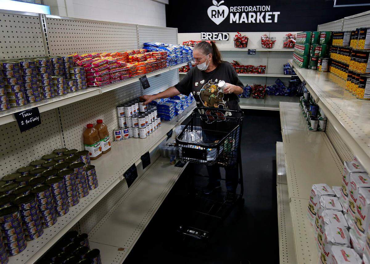 Linda Bossingham of Finley fills her shopping cart with a variety of items offered at the Restoration Community Impact market at 4000 W. Clearwater Ave. in Kennewick.