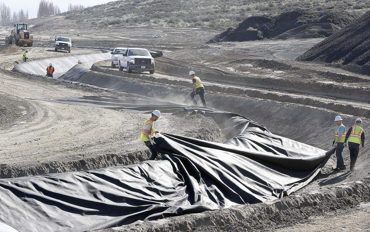 Kennewick Irrigation District employees spread an underliner in an empty irrigation canal off Highway 397 near Finely Road.