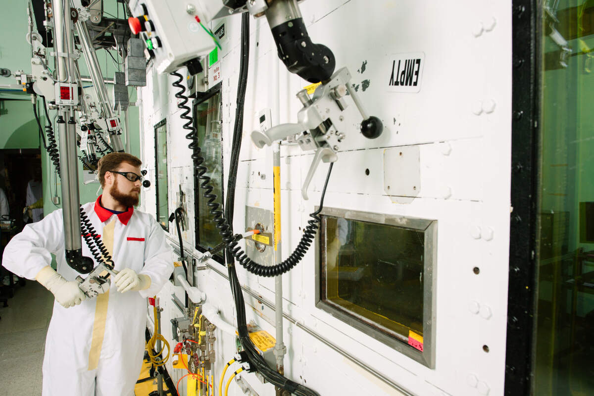 At the Hanford 222-S Laboratory, modern upgrades and new scientific methods have cut turnaround times for analyzing samples by 50%. Looking through shielded glass, scientist Caleb Mortensen guides a mechanical manipulator.