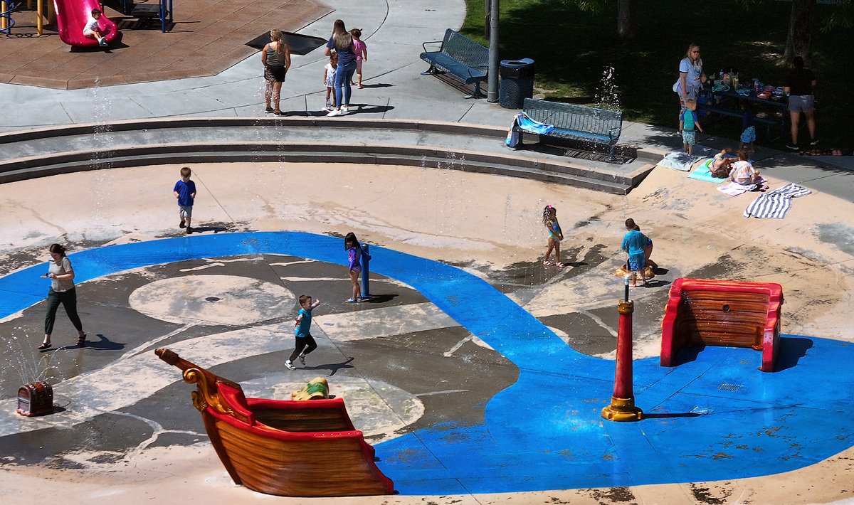 Children and parents gather around the pirate ship splash pad, playground equipment and picnic area Wednesday morning at the Highland Grange Park off South Union Street in Kennewick. The National Weather Service forecasts the first triple digit temperatures of the year on Sunday as the Pacific Northwest swelters under a heat wave