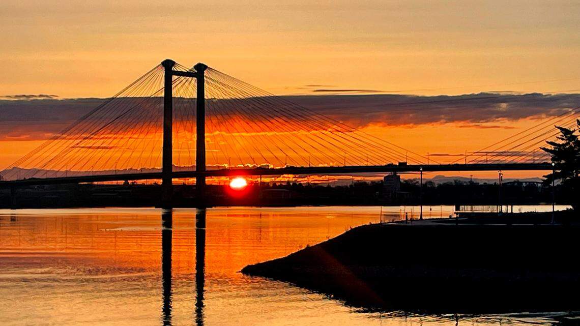The sun rises behind the cable bridge and Clover Island in Kennewick. The Tri-Cities is under an excessive heat warning through at least July 11, 2024.