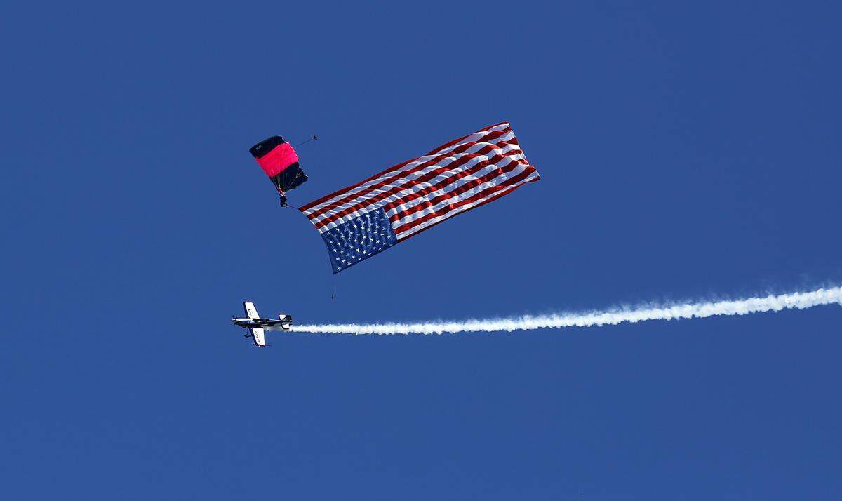Brad Wursten in his MX2 high-performance acrobtic airplane circles past Misty Blues skydiver Amanda Scheffler as she presents the colors over the Columbia River during the opening ceremony of Saturday's Over-The-River Airshow. The Misty Blues All Woman Skydiving Team has been performing at air shows, corporate events and other special occasions around the world since the early 1980s..