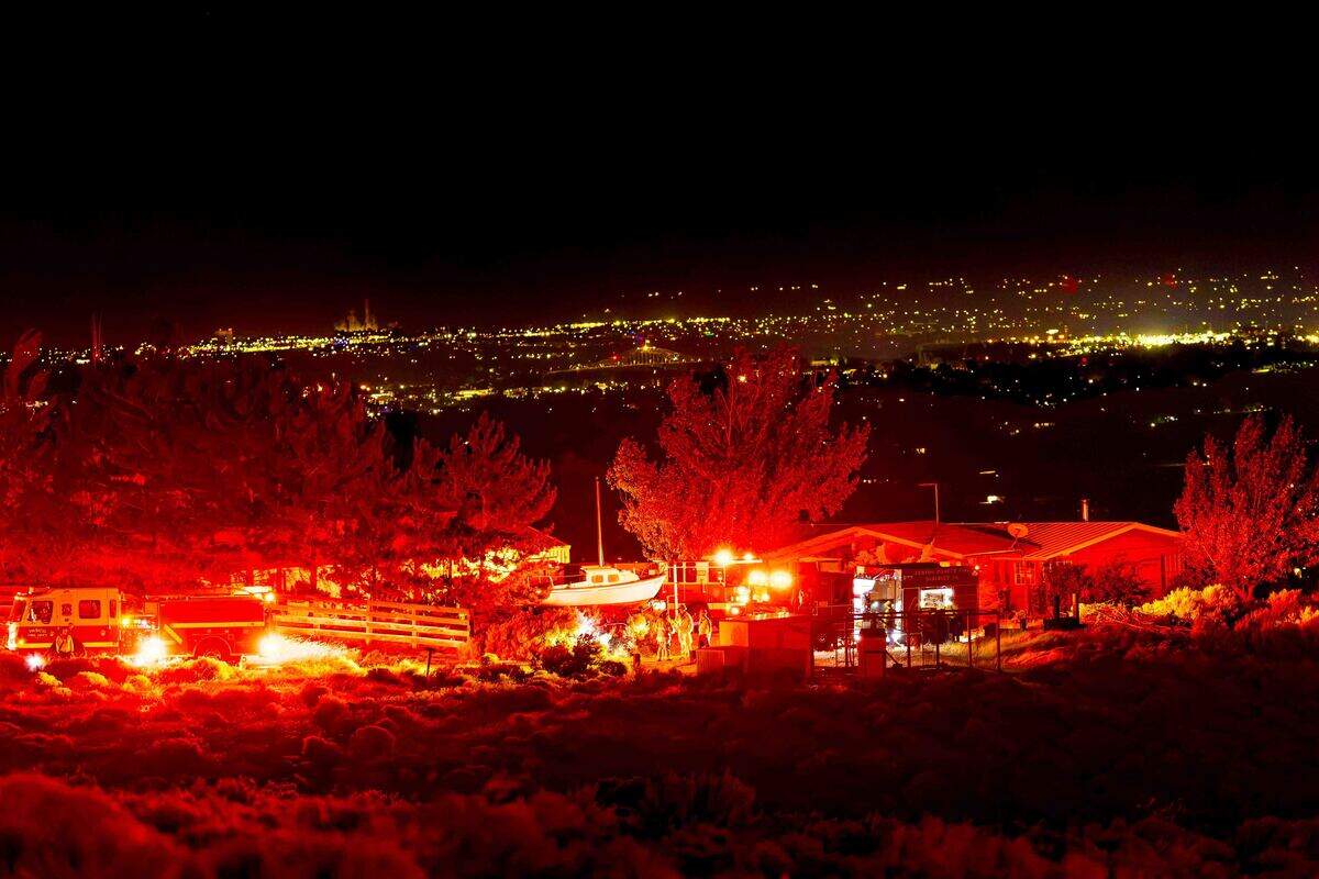 Emergency crews stage near homes threatened by the Nine Canyon Fire on Saturday morning near Kennewick. Evacuation notices were issued for nearby residents as firefighters worked to slow the wildfire’s advance toward Finley.