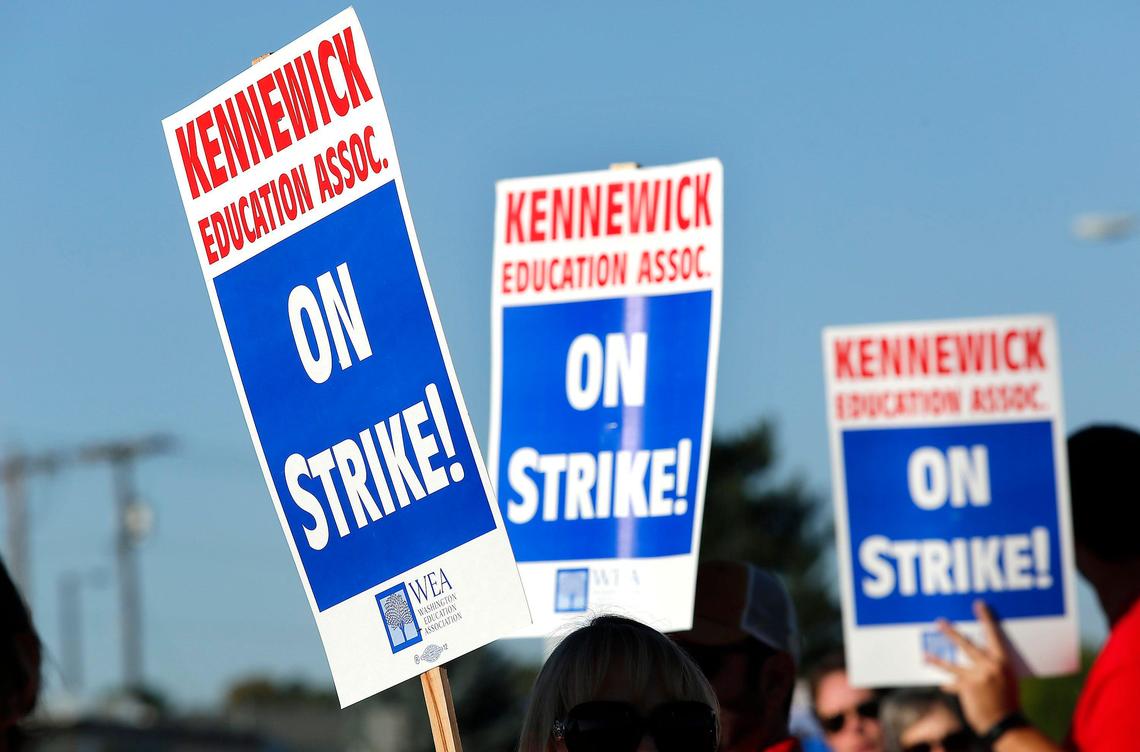 Striking Kennewick teachers and their supporters wave signs early Tuesday morning on West Vineyard Drive near Amistad Elementary School.