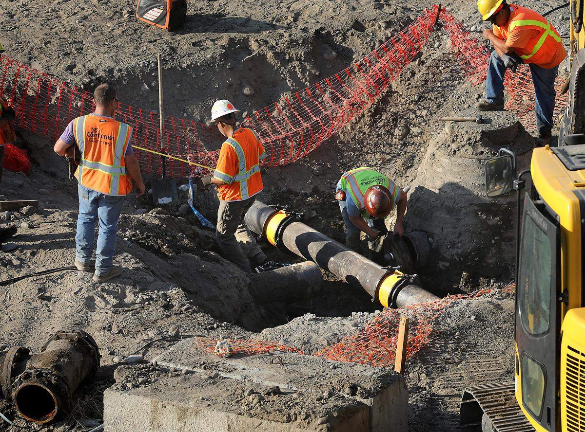 Crews cap off an old water main pipe after connecting a new one.