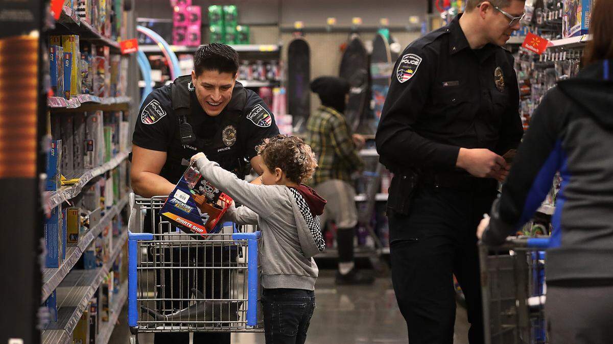West Richland Police Officer Zach Riojas helps Emerson Poppe fill a shopping cart with Christmas gifts Thursday morning during the annual Cops & Kids Christmas shopping event at the Richland Walmart store. About 30 officers and detectives from the Richland and West Richland helped 18 children shop for themselves or their loved ones.