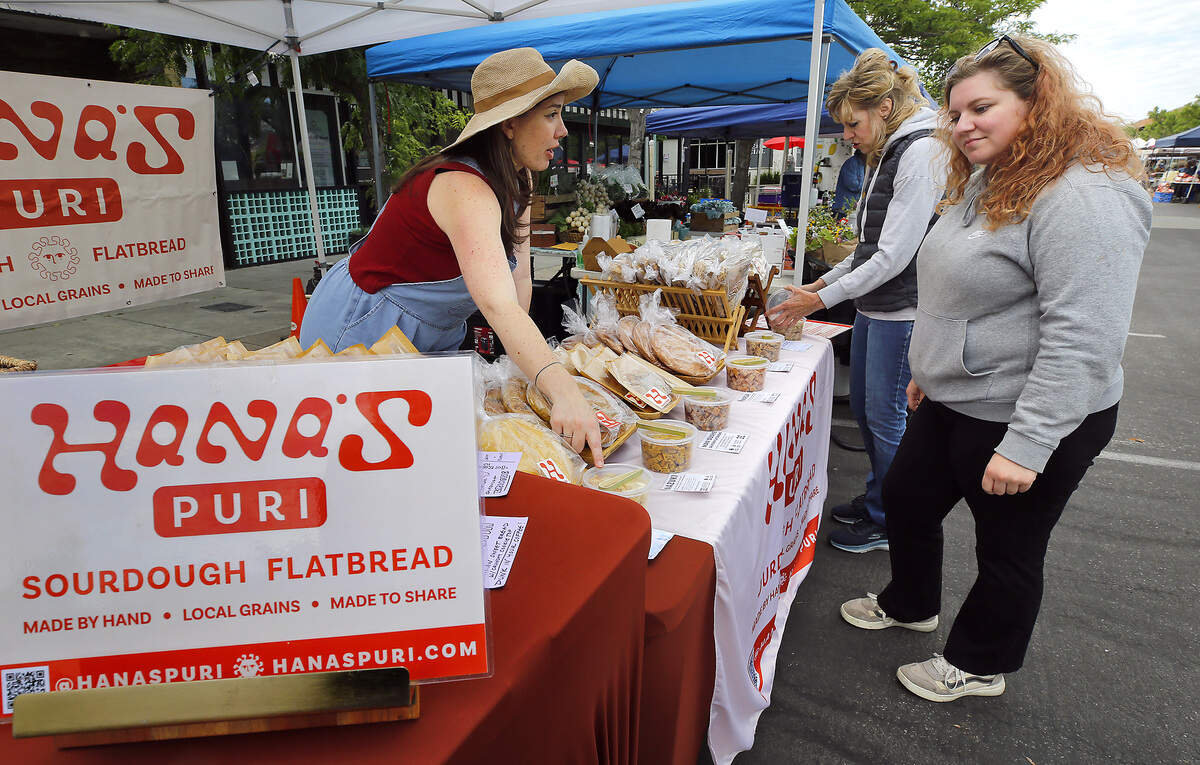 Jessica McPeak, an employee of Hana's Puri of Benton City, offers samples of handmade sourdough flatbreads to Tammy Mallon, middle, and Anne Marie Bartoscheck Friday morning's opening day of the Richland Farmers Markey.