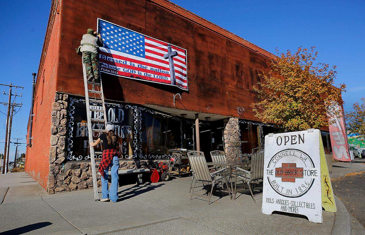 Dale Kuehny and his daughter, Jenni, work together to put up a banner on their family-owned business called The Old Brick Store in Connell.