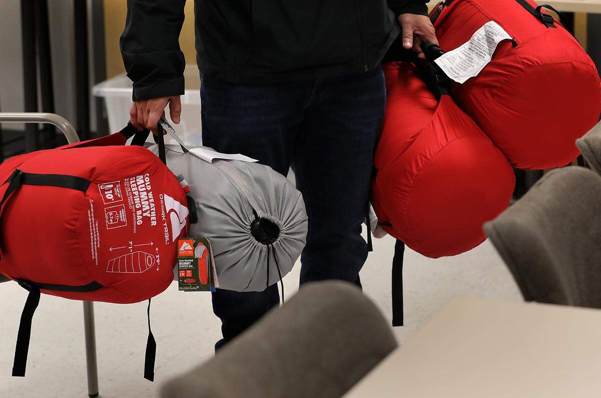 Volunteers for the annual Point in Time homeless count carry sleeping bags out of a meeting room at the Benton Franklin Health District for homeless people they encounter during the event..