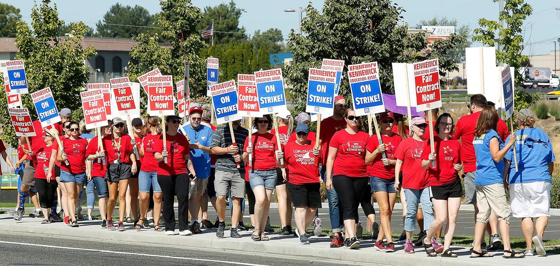 Striking Kennewick teachers and their supporters carry picket signs Tuesday on West Fourth Avenue near the Westgate Elementary School.