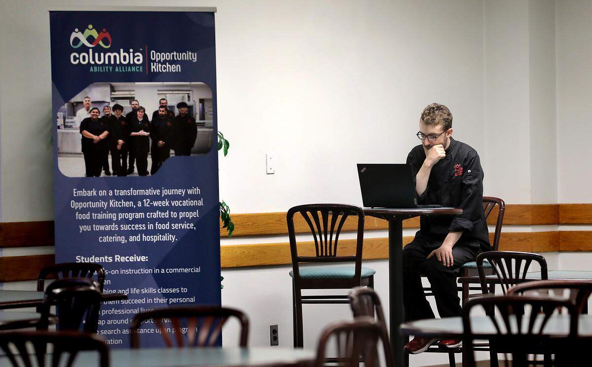 Student Chance Kloepper sits at a table in the Opportunity Kitchen restaurant space with a computer taking his food handler card online test. The 12-week program currently operates downstairs at the Federal Building in Richland.
