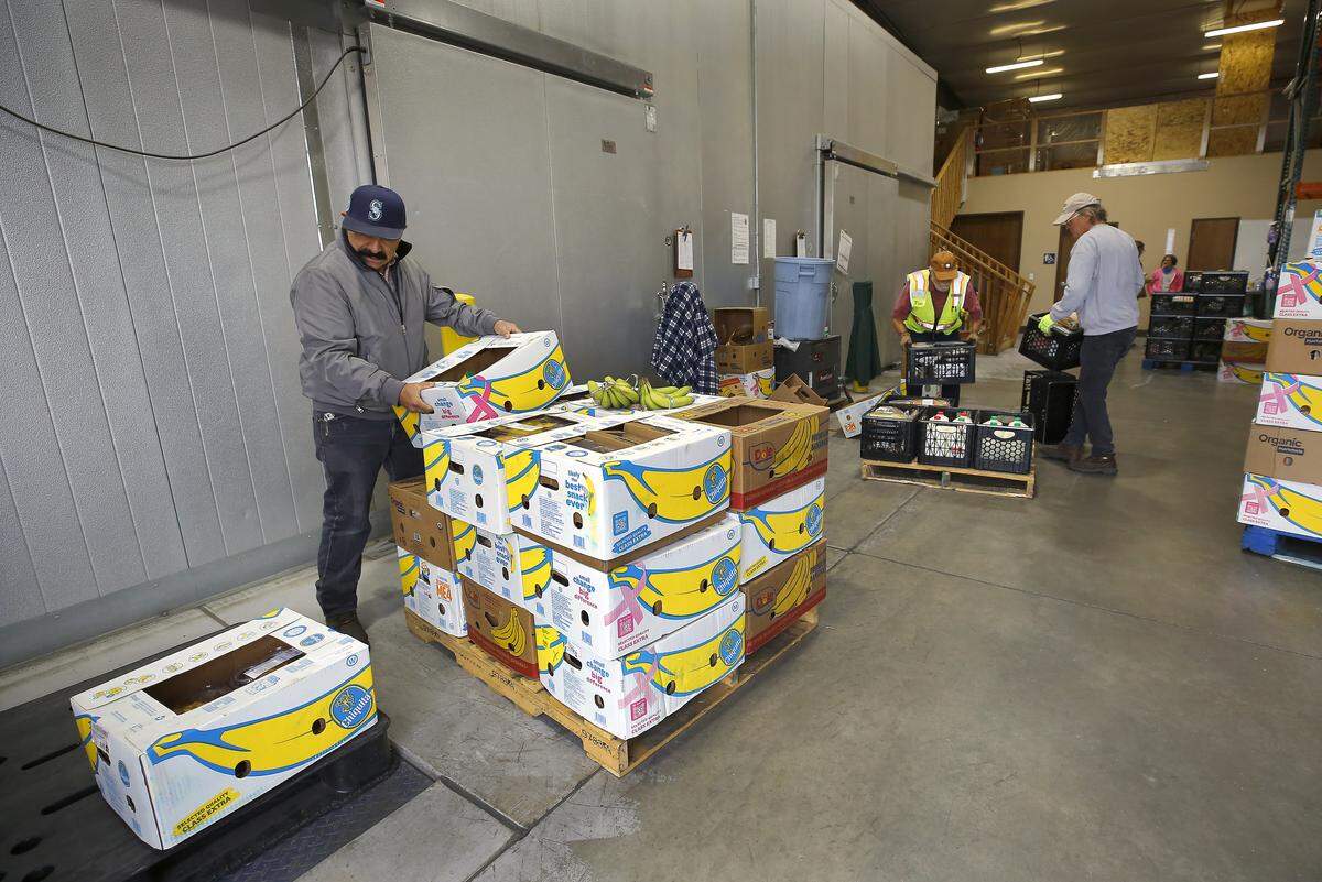 Warehouse manager Aurelio Meza, left, and volunteers Jay Willams and Jim Mahoney, right, sort and separate pallets of boxed food Monday in preparation for Wednesday's food distribution at the St. Vincent de Paul Food Bank in Pasco.