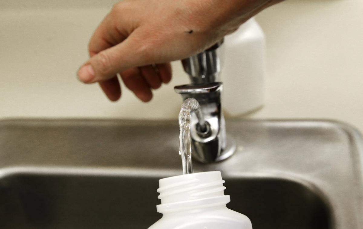 In this photo taken May 3, 2016, Donna McNeal, of Orion Environmental Services, collects a water sample from a classroom drinking fountain for lead testing at Fawcett Elementary School in Tacoma, Wash. (AP Photo/Ted S. Warren)