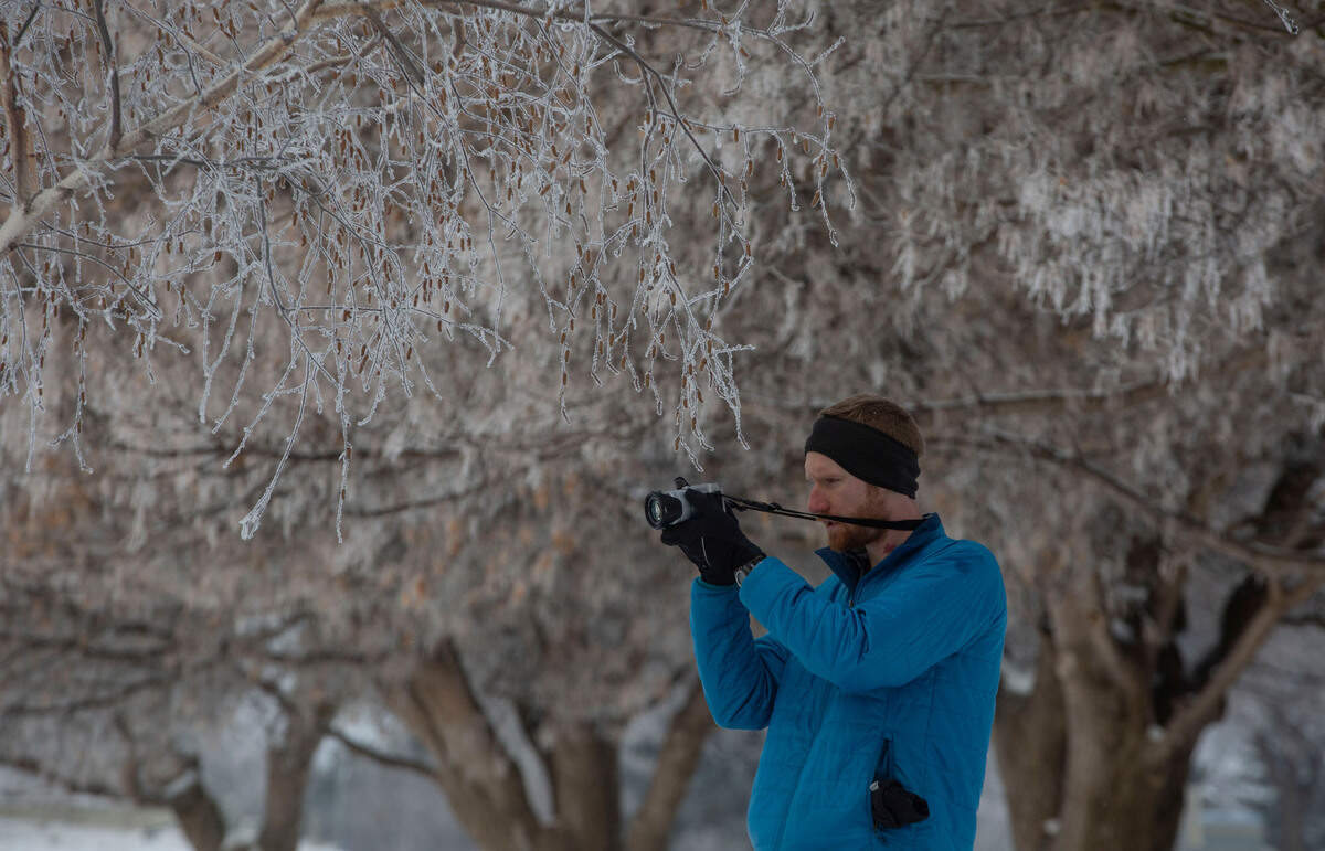 Micah Donor, 28, of Richland captures photos of the frost-covered trees in Leslie Groves park on Tuesday morning.