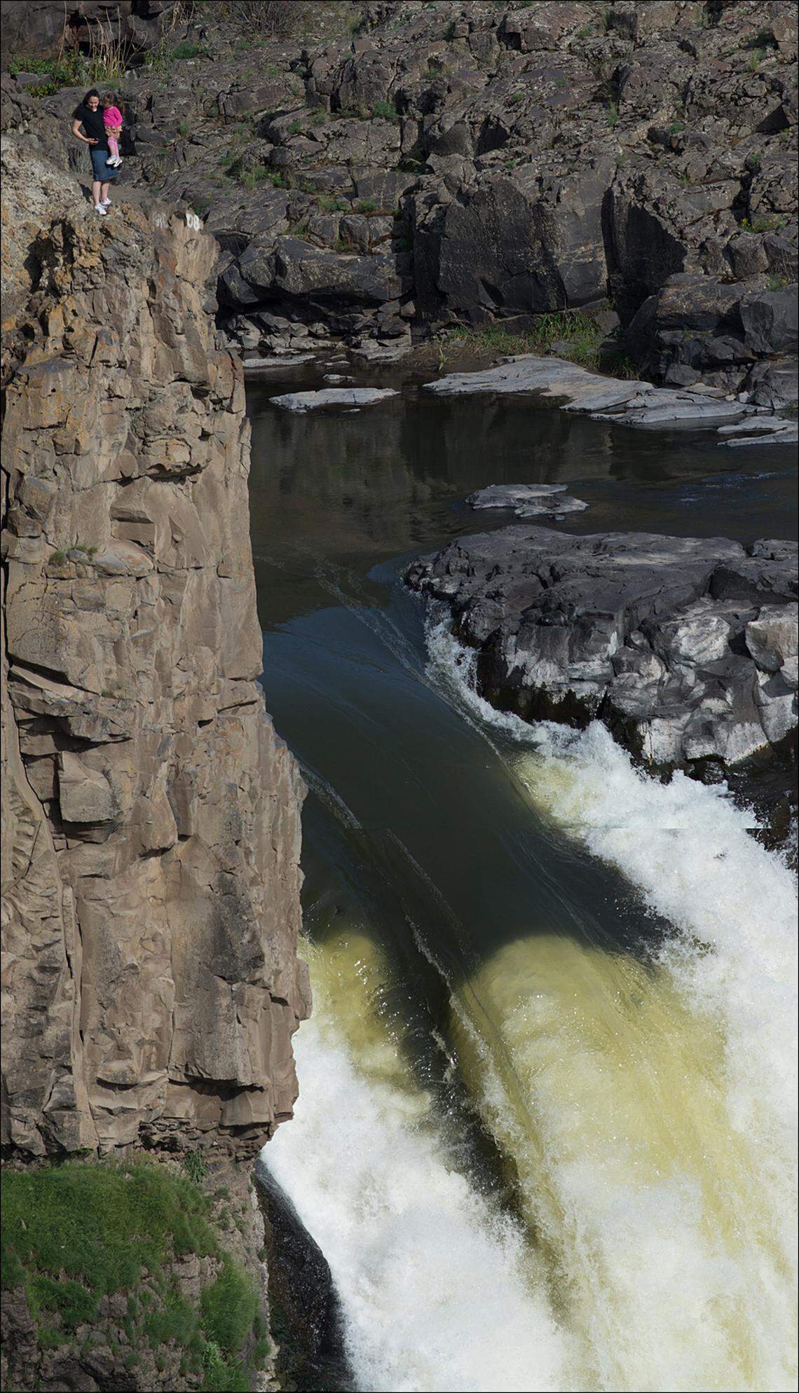 In this 2016 photo at Palouse Falls, a woman holds a child in her arms standing close to the cliff above the 200-foot drop.