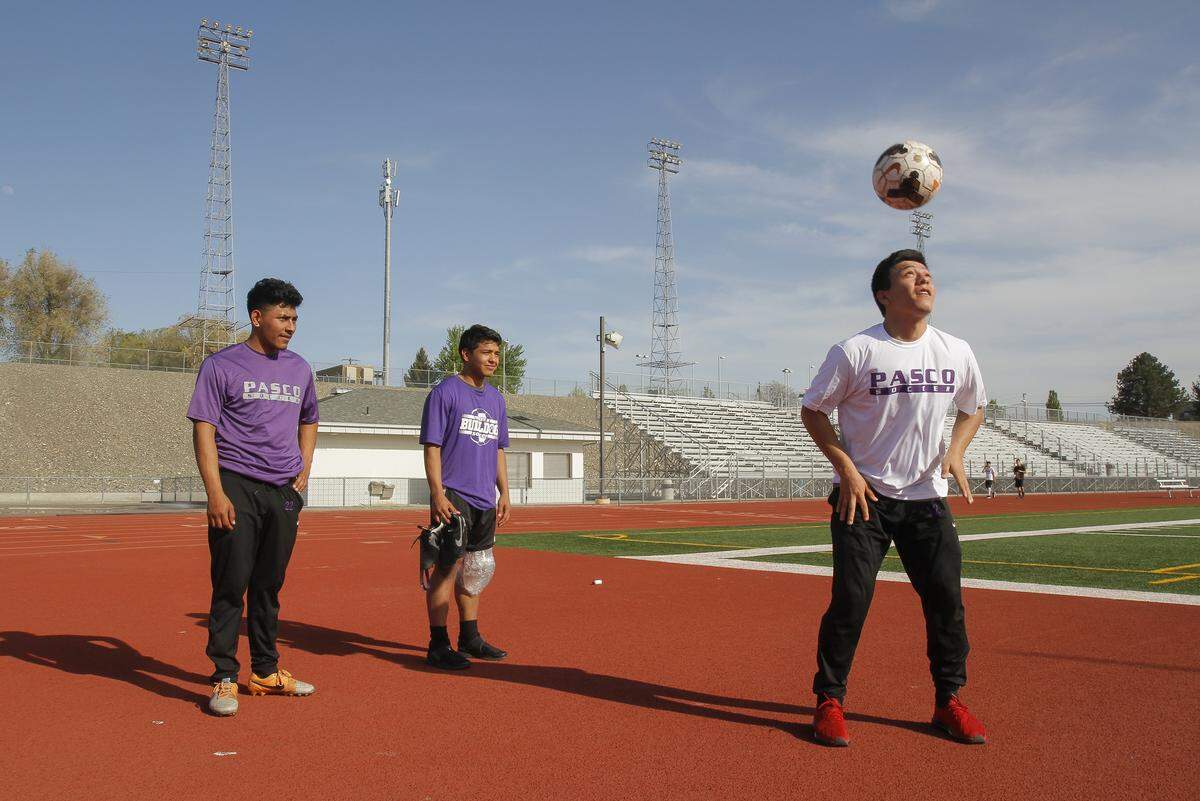 Siblings Jesus, left, and Kevin watch their brother, Emilio Meraz-Rodriguez plays around with the soccer ball at Edgar Brown Memorial in Pasco.