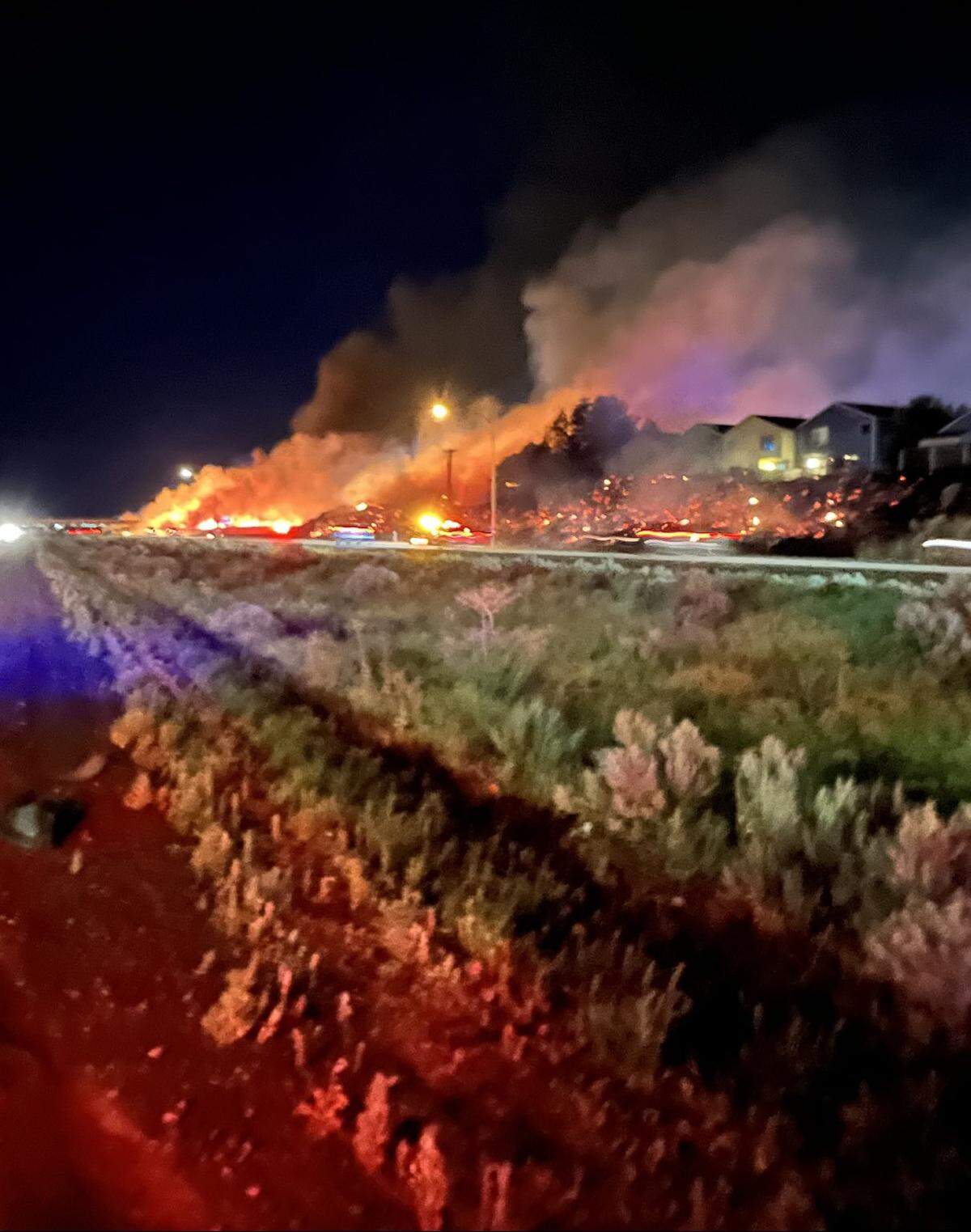 A wildfire threatened homes after starting in spots along nearly a mile of Interstate 182 in south Richland Saturday night.