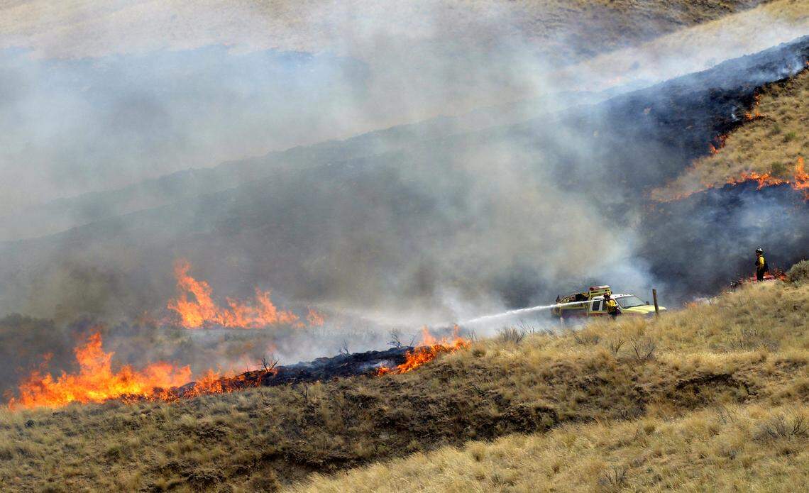 Shifting winds push flames from a spot fire away from firefighters as they perform a burnout operation in 2007 on McBee Road near Kiona.