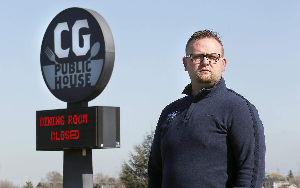 Kyle Simmons, director of operations at CG Public House & Catering, stands in May 2020 near the sign announcing closure of the dining room at the start of the pandemic. It’s now reopened.