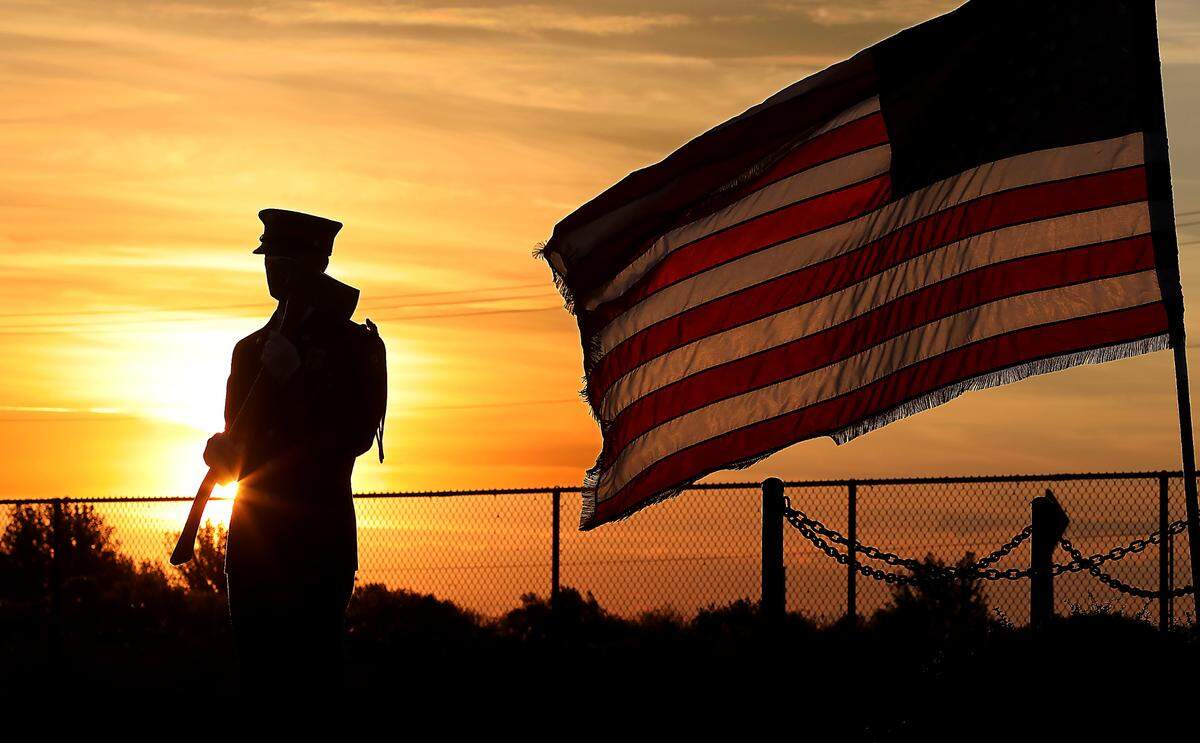 A member of Tri-Cities Professional Firefighters Honor Guard stands watch as the early morning sun rises over the 9/11 memorial in Kennewick.